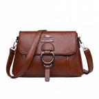 Bolsa clutch feminina transversal marrom de couro sintético com aba e argola prateada, vista de frente