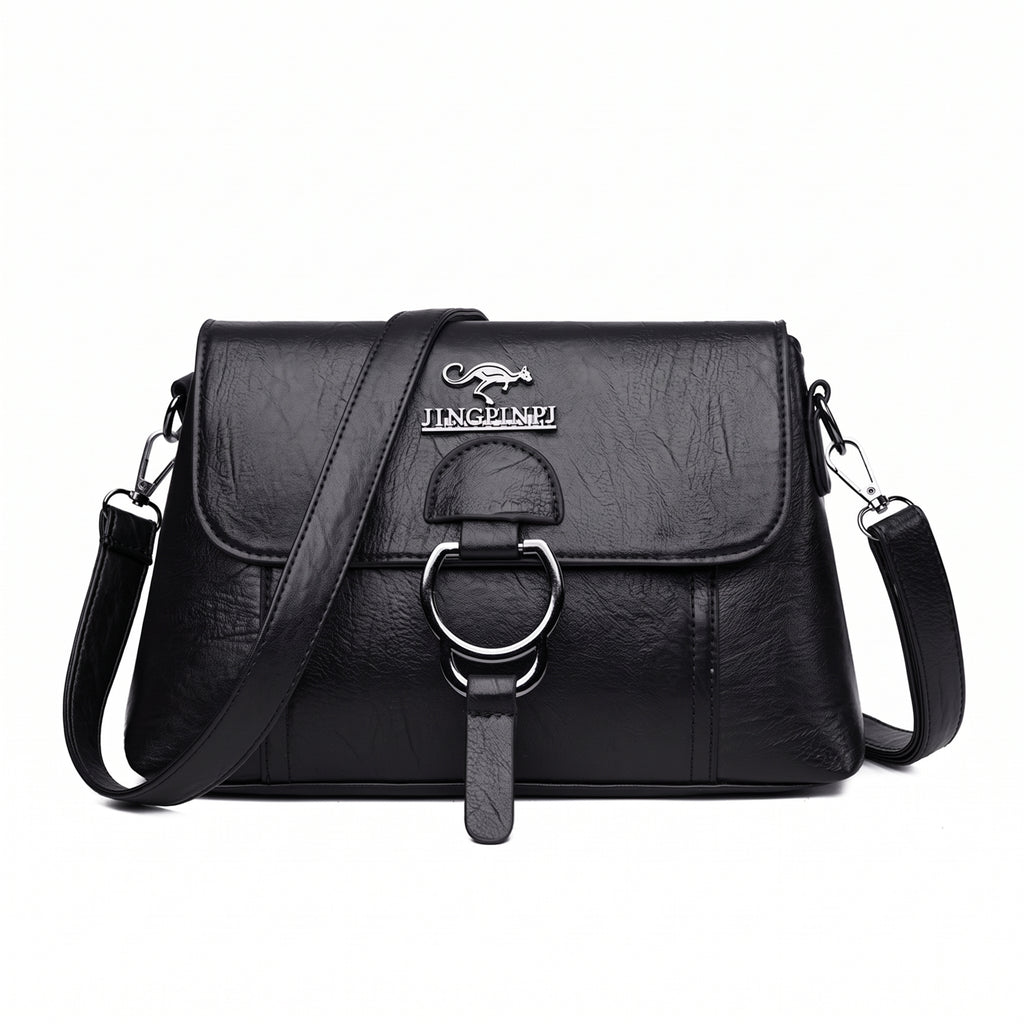 Bolsa clutch feminina transversal preta de couro sintético com aba e argola prateada, vista de frente