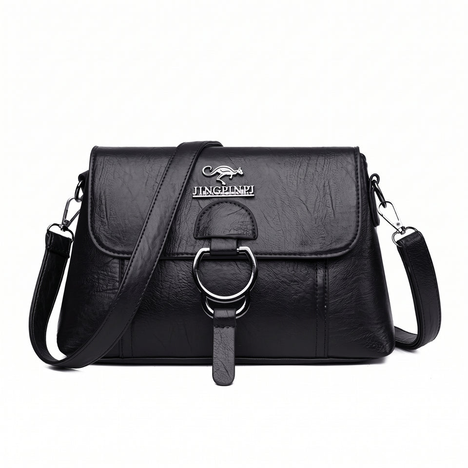Bolsa clutch feminina transversal preta de couro sintético com aba e argola prateada, vista de frente
