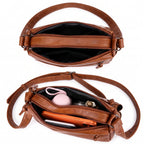 Bolsa crossbody caramelo aberta mostrando o compartimento principal e os bolsos internos com batom, chaves e maquiagem
