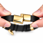 Mãos abrindo o fecho dourado de aço inox da pulseira masculina de couro